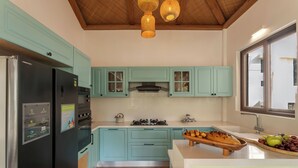 Una cocina moderna con armarios color turquesa, un refrigerador de acero inoxidable, una estufa a gas y encimeras de madera.