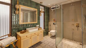 Un baño moderno con ducha envuelta en vidrio, un espejo grande y un mueble de tocador de madera.