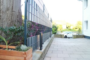 A building with a modern facade, a paved walkway, and a parked car. - Steinberger Hof Übernachtungen (Rinteln)