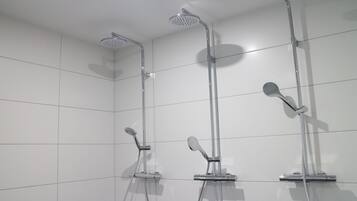 Um chuveiro moderno com três cabeças e um chuveiro manual.