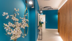 A hallway with a blue wall, a white vase with white flowers, and modern wall sconces. - Estudio Oriente - Design et confort dans DELICIAS MADRID (Madrid)