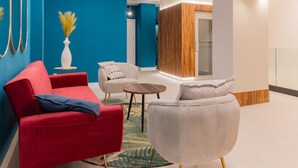 A modern waiting area with red and white sofas, a small round table, and a decorative vase. - Estudio Oriente - Design et confort dans DELICIAS MADRID (Madrid)
