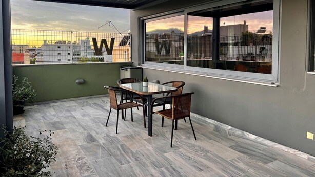 Ein Balkon mit Tisch und Stühlen, Blick auf die Stadtlandschaft und ein großes 'W' Schild an der Wand.