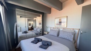 Ein Hotelzimmer mit zwei Betten, einem großen Spiegel, einem gerahmten Bild an der Wand und einer Tür.