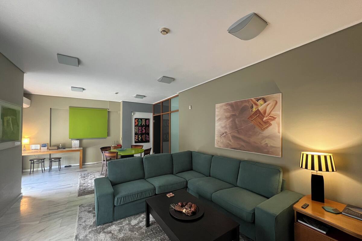 Una sala de estar moderna con un sofá seccional verde, una mesa de centro negra y un cuadro en la pared.