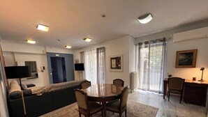 Ein modernes Wohnzimmer mit Essbereich, einer Couch, einem Couchtisch und einem an der Wand montierten Fernseher.