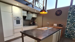 A modern kitchen with a central island, stainless steel appliances, and a large window providing natural light. - Cozy cottage in Athienville (Athienville)