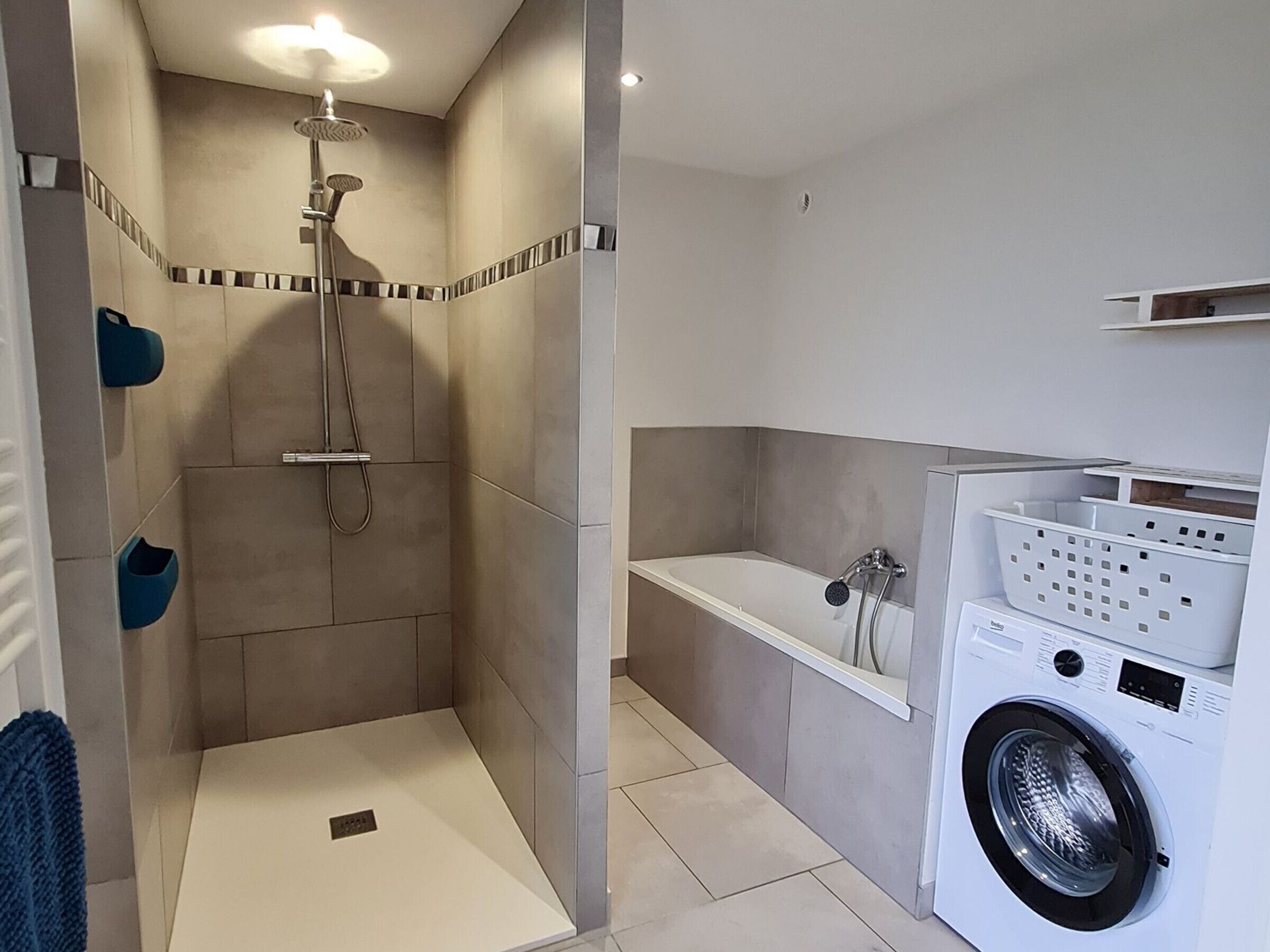 A modern bathroom with a shower, a bathtub, and a built-in washing machine.