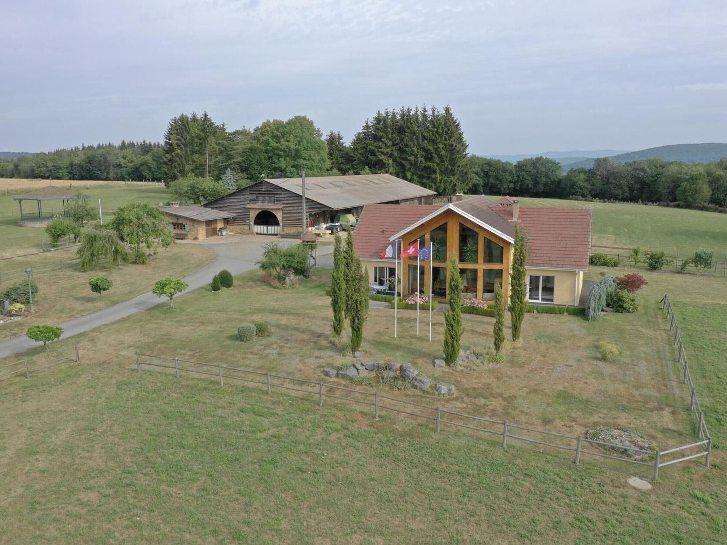 A rural property with a main house, a barn, and a fenced area.