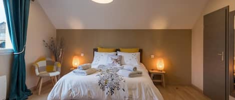 Un dormitorio moderno con cama, lámparas de noche, una silla y vistas al exterior.