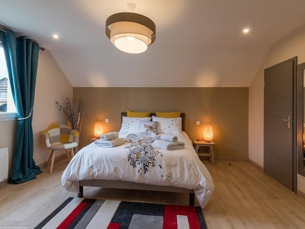 A modern bedroom with a bed, bedside lamps, a chair, and a view of the outside. - Charming room for 2 with sauna and bikes in Vyans-le-Val (Vyans-le-Val)