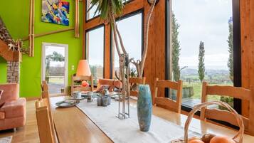 Un coin repas avec une table en bois, des chaises, un vase et un panier de fruits.