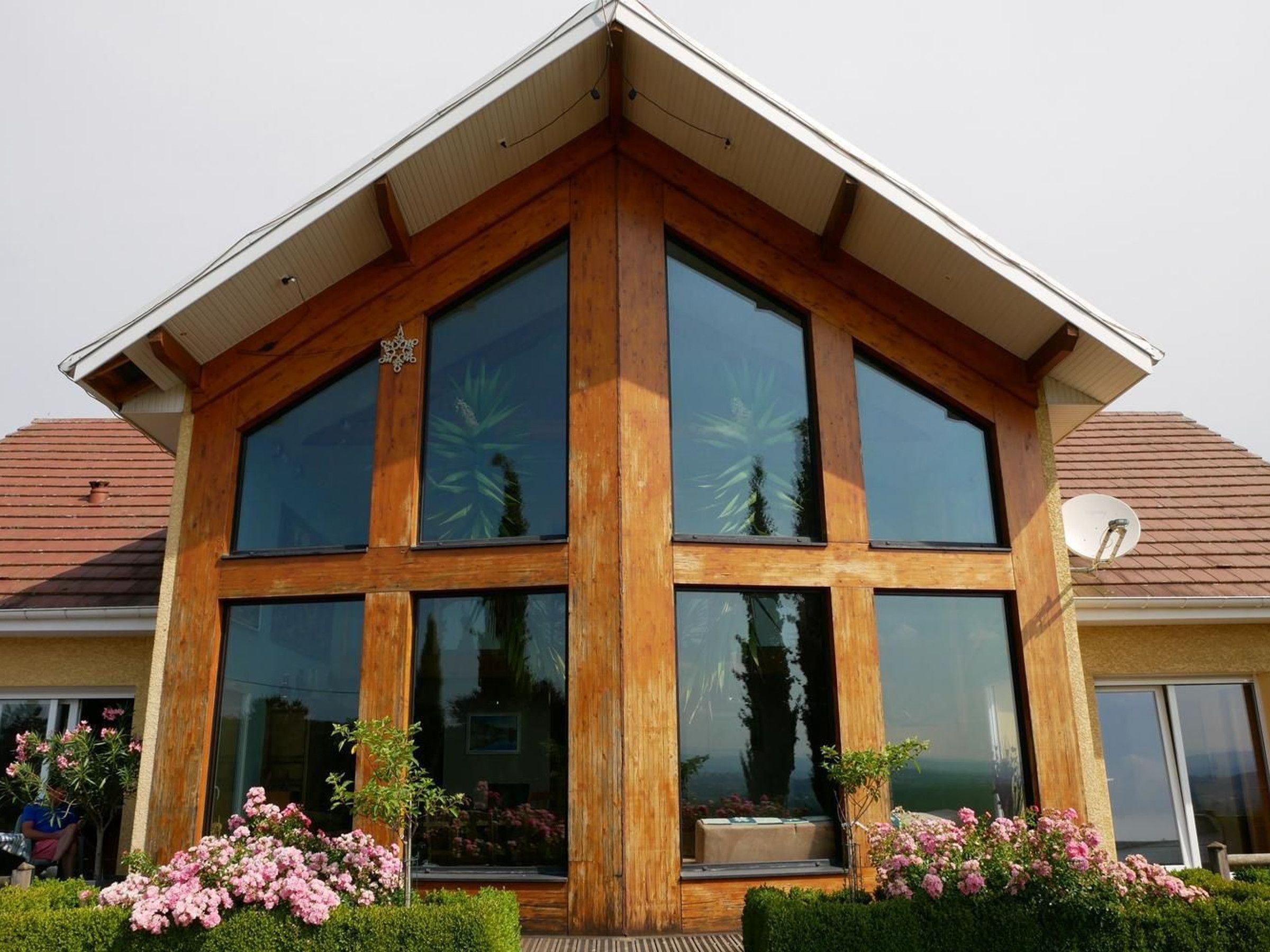 Une maison moderne dotée de grandes fenêtres et d’un toit en pente.