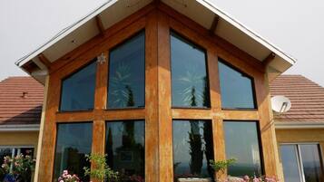 Une maison moderne dotée de grandes fenêtres et d’un toit en pente.