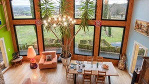 Une pièce spacieuse avec de grandes fenêtres, une table à manger, un canapé et un lustre.