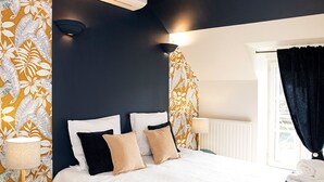 Une chambre d’hôtel avec un lit, deux tables de chevet, une fenêtre avec des rideaux et un radiateur.