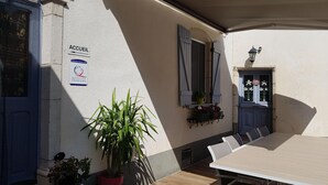An outdoor patio area with a table and chairs, a potted plant, and a sign indicating a quality tourism service. - Cozy room in historic house with park and horse facility (Choye)