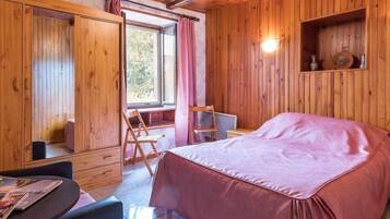 Een houten kamer met een bed, een tafel en een stoel.