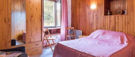 A wooden room with a bed, a table, and a chair.