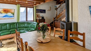 Una habitación acogedora con un sofá de cuero verde, una mesa de comedor de madera y una chimenea.