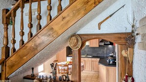 Una escalera de madera de estilo rústico que conduce a una zona de cocina con armarios de madera y una mesa de comedor.