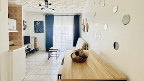 Ein moderner Wohnraum mit Esstisch aus Holz, einer Küchenzeile und Blick durch ein großes Fenster.