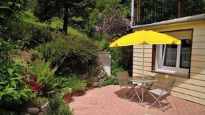 A patio with a yellow umbrella, a table, and two chairs.
