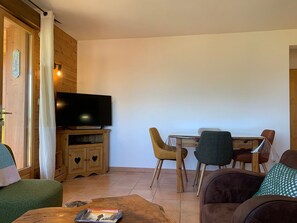 Ein Wohnzimmer mit Fernseher, Holzmöbeln und einem Essbereich mit Stühlen.