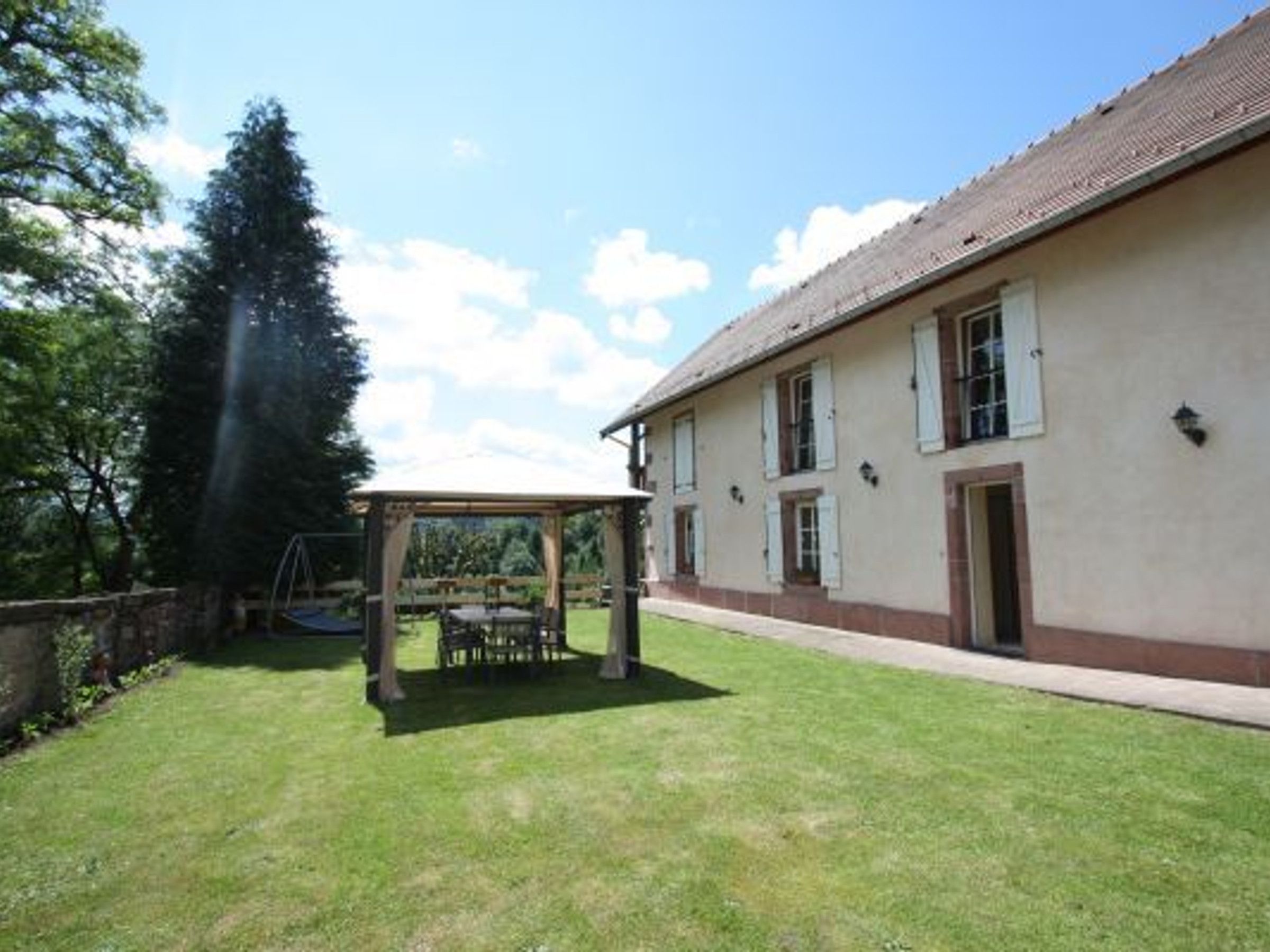 Une maison avec un patio couvert, une pelouse et un grand arbre.