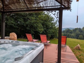 A hot tub with a wooden deck and red chairs, surrounded by trees and a view of hills. - Coquelicot Room, peaceful nature retreat from the 18th century, breakfast included (Moyenmoutier)