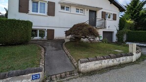 A two-story residential building with a paved driveway and a small garden area. - Cozy studio with terrace near Epinal, parking included (Dinozé)