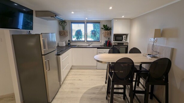A modern kitchen with a built-in oven, microwave, and a large window. - Cozy studio with terrace near Epinal, parking included (Dinozé)
