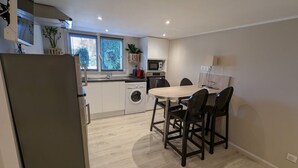 A compact kitchen with a washing machine, a microwave, and a dining area with chairs. - Cozy studio with terrace near Epinal, parking included (Dinozé)