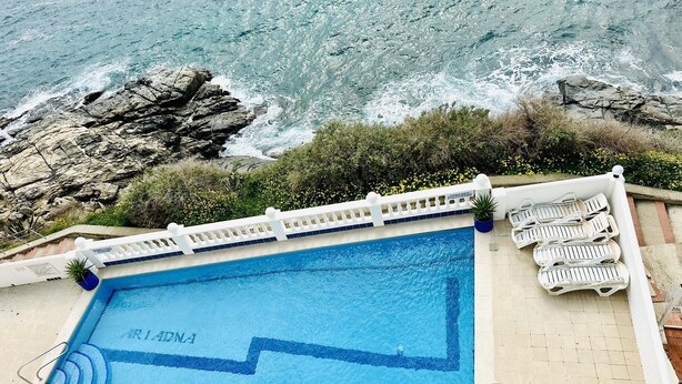 A pool with a view of the ocean, surrounded by a white fence and lounge chairs. - ARIADNA B. Apartamento amplio para 6 en Roses – vistas al mar (Roses)