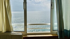 A room with a large window, curtains, and a view of the sea. - ARIADNA B. Apartamento amplio para 6 en Roses – vistas al mar (Roses)