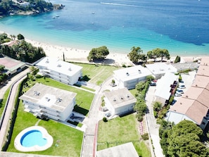 An aerial view of a coastal hotel with multiple buildings, a swimming pool, and a beach. - Luxury Seafront Apartment with Private Terrace (Roses)