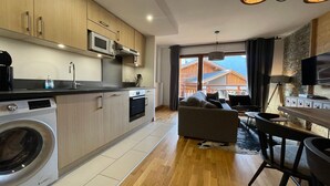Et moderne køkken med indbyggede apparater, et spiseområde med bar samt en opholdsstue med sofa.