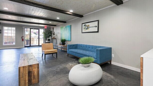A modern lobby with a blue sofa, wooden coffee table, and a round white table with a plant.
