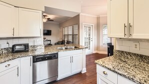 A kitchen with white cabinets, granite countertops, stainless steel appliances, and a built-in dishwasher.