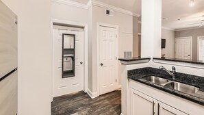 A kitchen with white cabinetry, a black granite countertop, and a stainless steel sink.