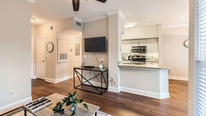 Una cocina moderna con microondas y horno integrados, un comedor con mesa y sillas de madera, y un ventilador de techo.