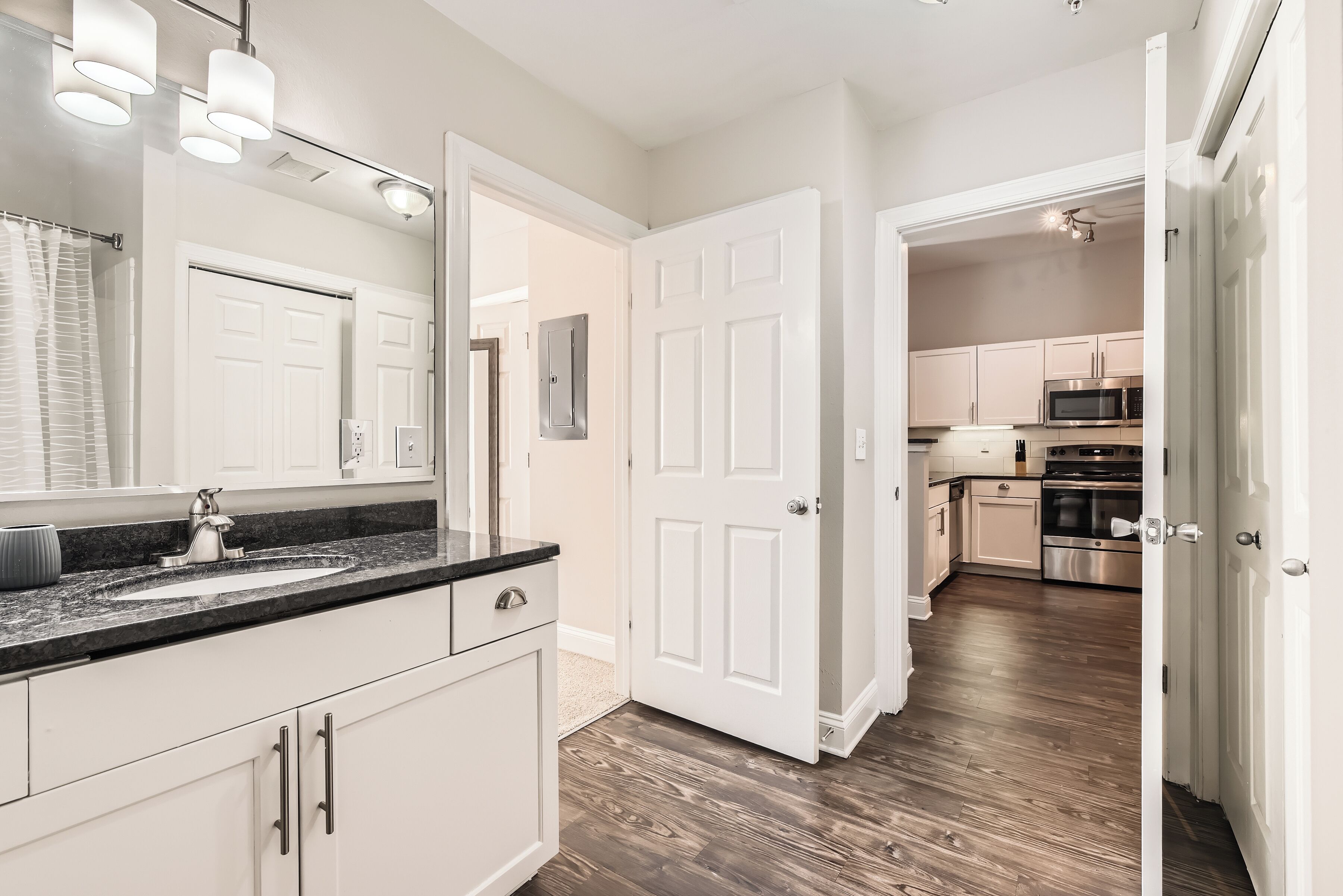 A modern kitchen with white cabinets, a stainless steel microwave, and an oven.