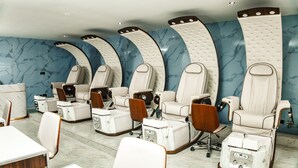 A salon with multiple massage chairs, wooden chairs, and a marble wall. - Swiss International Rancho Valeria (Warri)