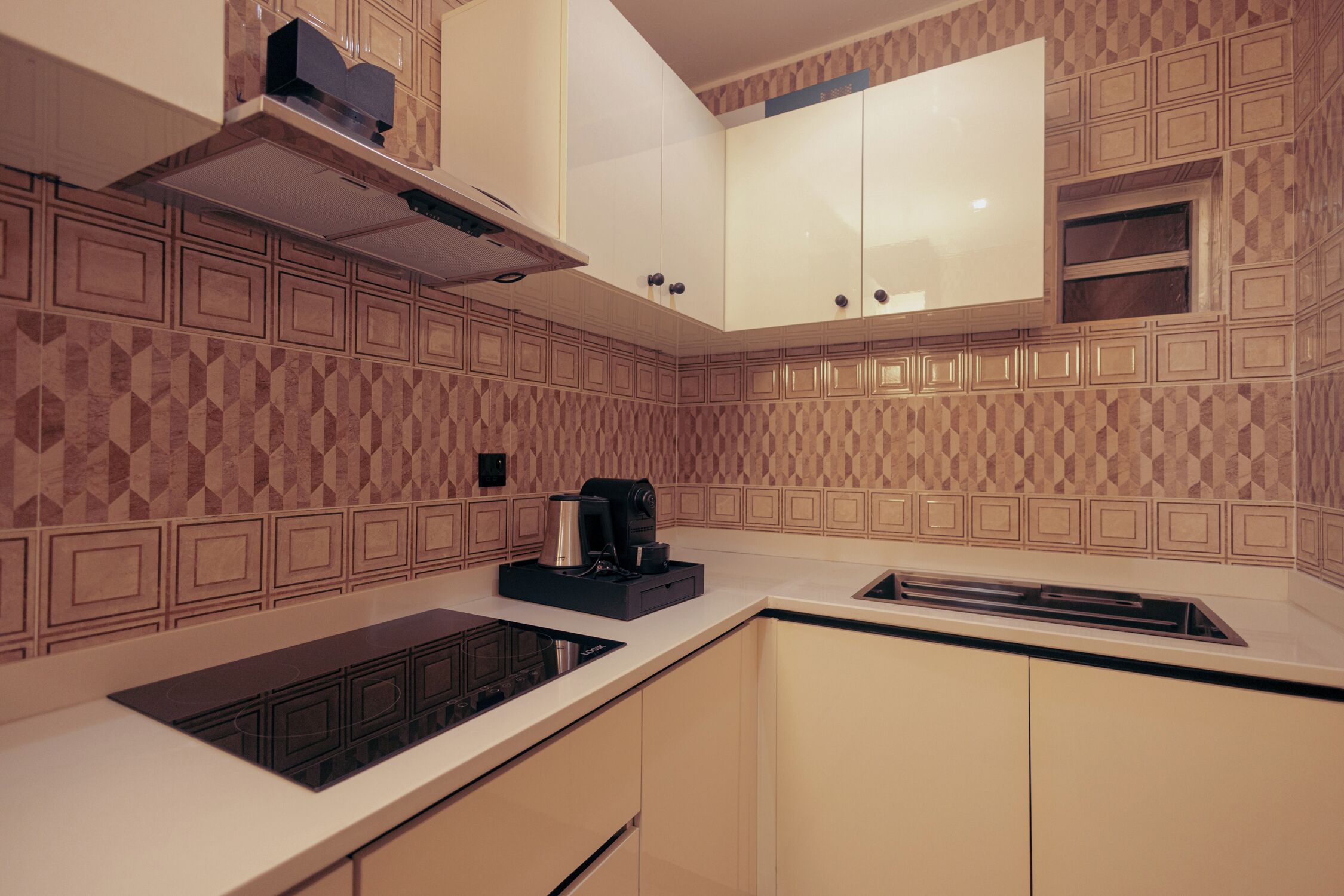 A modern kitchen with patterned backsplash, white cabinets, and a built-in stove.