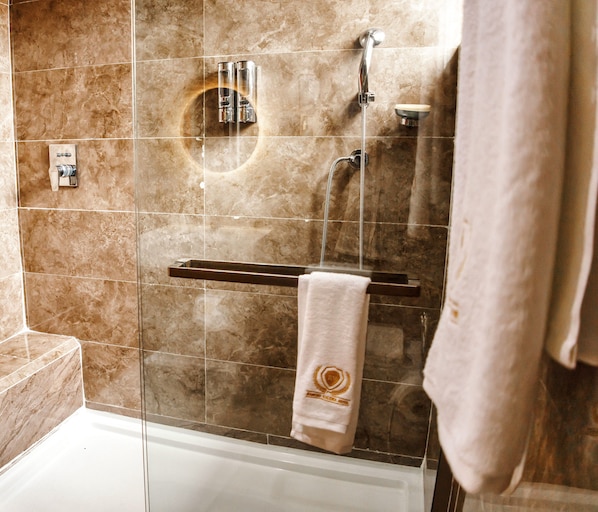 Une salle de bain moderne avec une douche en verre, un porte-serviettes et un mur recouvert de carreaux de marbre.