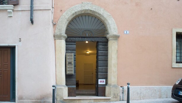 A building entrance with a stone archway, a door, and a small sign above the door. - VERONA EASY LOFT - ID M0230911208 (Verona)