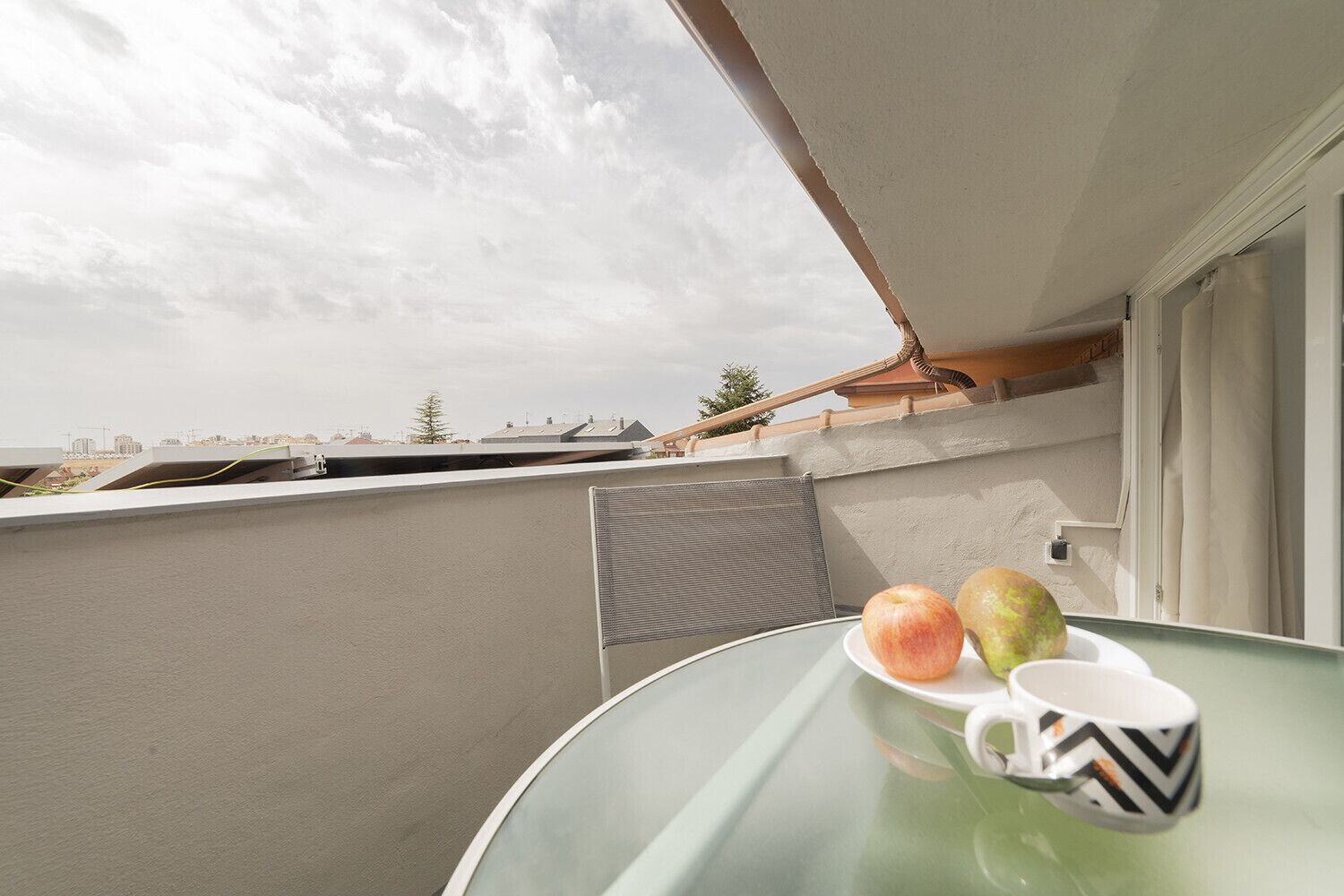 Ein Balkon mit Tisch, zwei Äpfeln und einer Tasse.