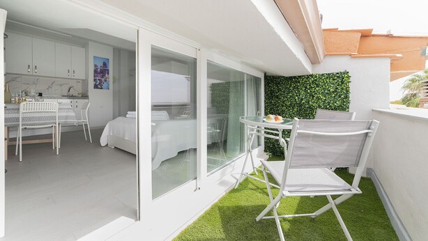 Eine moderne Wohnung mit Balkon, Essbereich und einem Schlafzimmer mit Glastür.