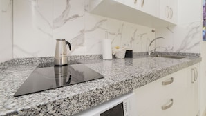 Eine moderne Küche mit Granit-Arbeitsplatte, einer Kaffeemaschine, einem Korb und einem Spülbecken.