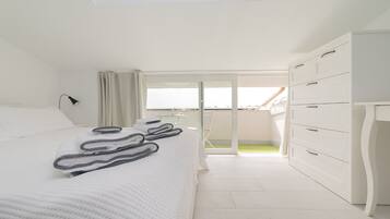 A bedroom with a large bed, a wardrobe, and a balcony with a view.